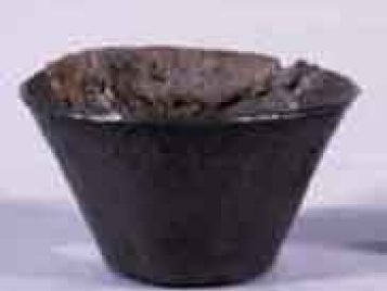 Small, corroded silver cup before conservation treatment.